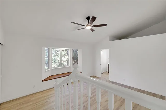 a view of empty room with wooden floor and fan