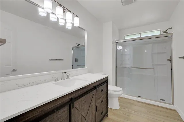 a bathroom with a sink a toilet a shower and a large mirror