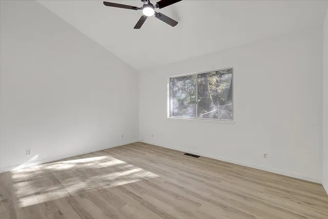 a view of a room with wooden floor and a ceiling fan