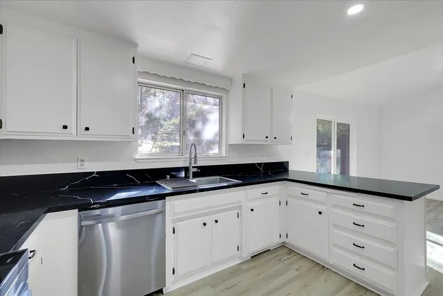 a kitchen with granite countertop white cabinets and sink