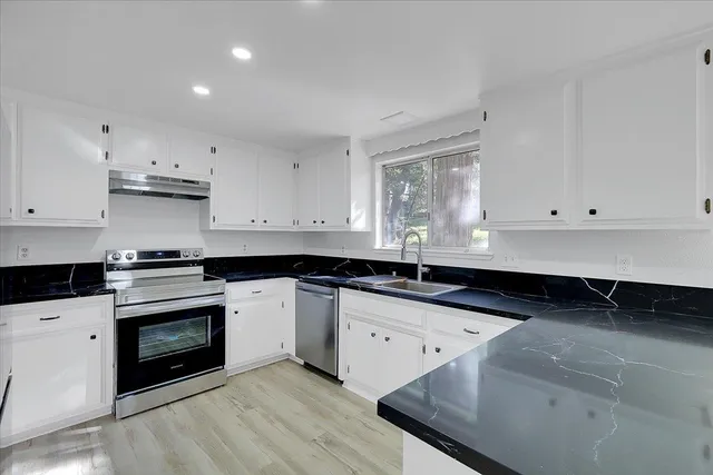a kitchen with granite countertop white cabinets and a stove