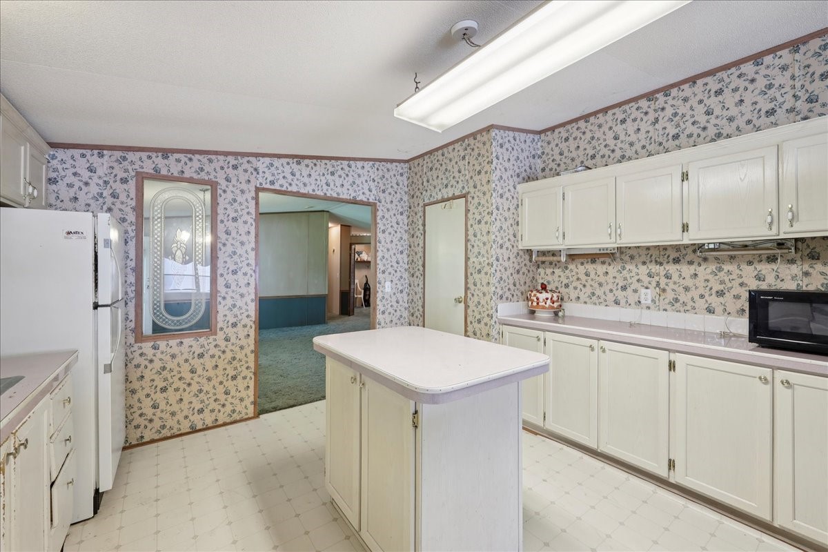 6505 County Road 200 Brookeland, TX 75931 - Photo 19 of 34 a kitchen with white cabinets a sink stove and refrigerator
