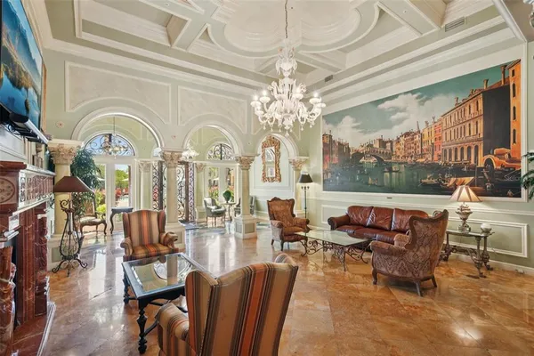 a living room with furniture a chandelier a large window and a fireplace