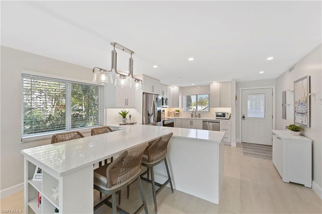 1686 Blue Point Avenue, Unit B5 Naples, FL 34102 - Photo 10 of 46 a large kitchen with a table and chairs