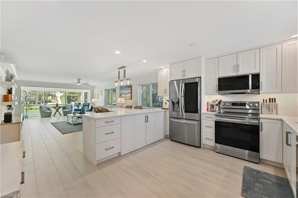 1686 Blue Point Avenue, Unit B5 Naples, FL 34102 - Photo 45 of 46 a kitchen with stainless steel appliances granite countertop a stove top oven a sink dishwasher a dining table and chairs with wooden floor