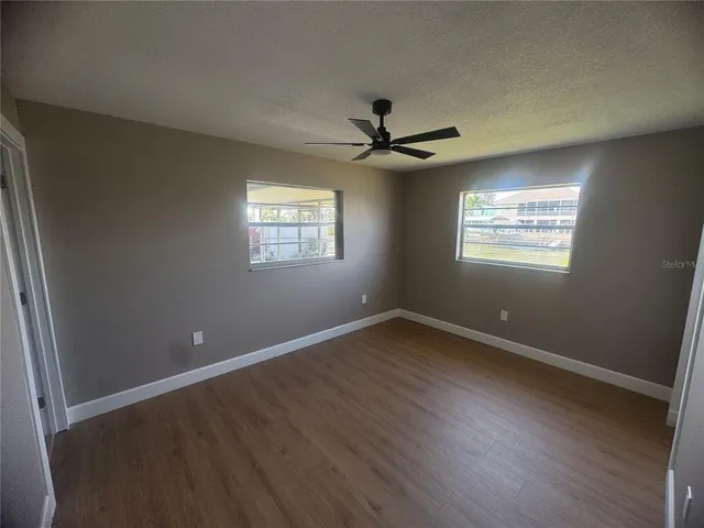 a view of an empty room with a window and wooden floor