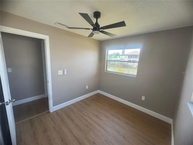 an empty room with wooden floor fan and windows