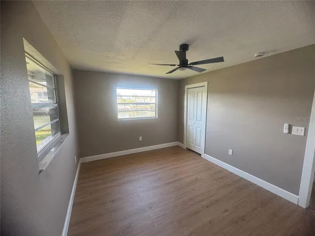 a view of an empty room with a window and wooden floor