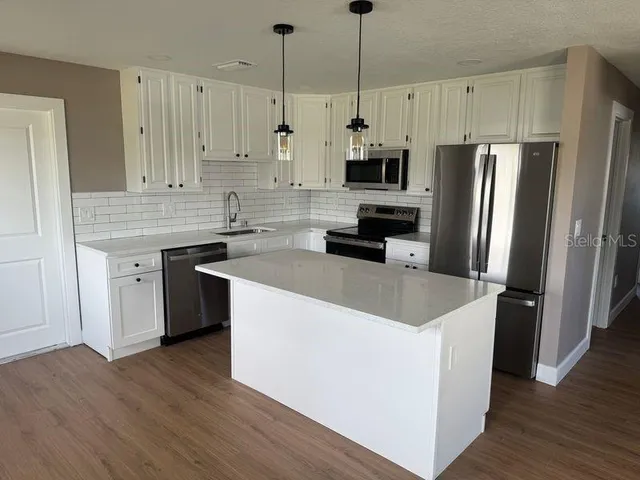 a kitchen with stainless steel appliances granite countertop a refrigerator a sink dishwasher a stove and a refrigerator