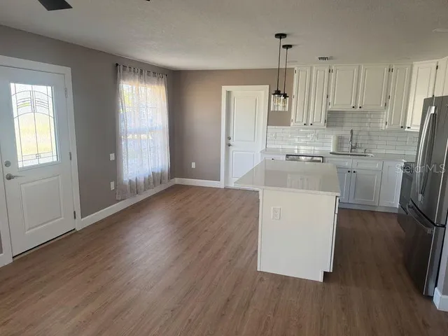 a kitchen with stainless steel appliances a refrigerator a stove a sink and white cabinets