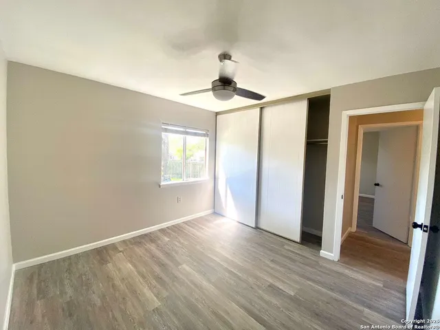 a view of empty room with wooden floor and fan
