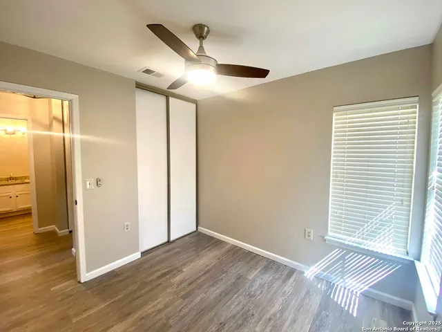an empty room with wooden floor cabinet and windows