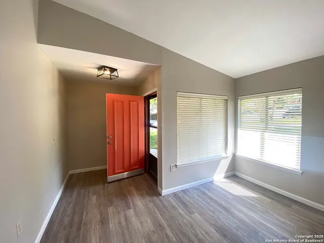 an empty room with wooden floor and windows