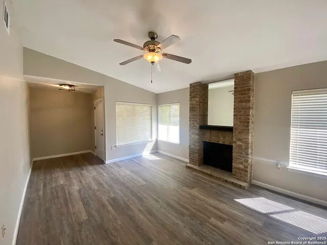 a view of an empty room with window and wooden floor