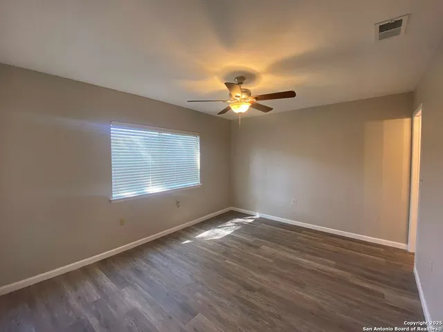 a view of an empty room with a window and wooden floor