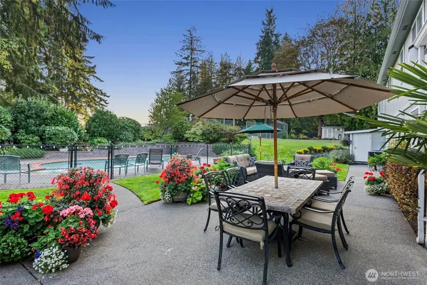 a view of a chairs and table under an umbrella in the backyard
