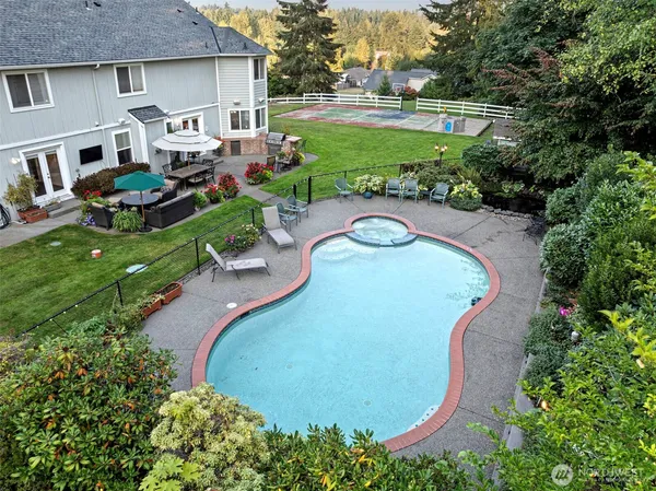 an aerial view of a house with outdoor space and trees all around
