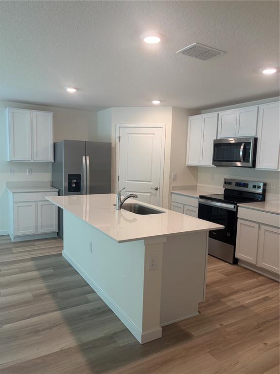 15886 Southeast 101st Ct Road Summerfield, FL 34491 - Photo 3 of 14 a large kitchen with stainless steel appliances wooden cabinets and a wooden floor