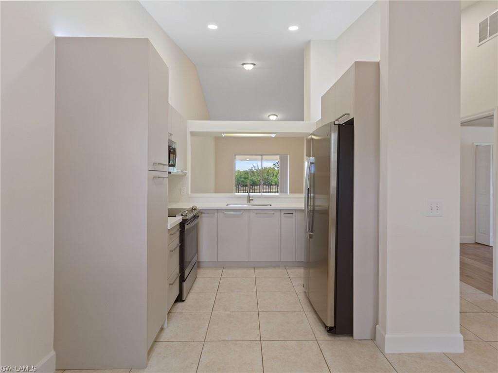 445 Robin Hood Circle, Unit 202 Naples, FL 34104 - Photo 6 of 23 a kitchen with a refrigerator and a sink