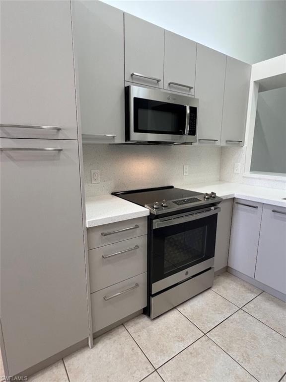 445 Robin Hood Circle, Unit 202 Naples, FL 34104 - Photo 7 of 23 a kitchen with stainless steel appliances white cabinets and a stove top oven