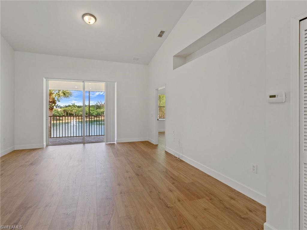 445 Robin Hood Circle, Unit 202 Naples, FL 34104 - Photo 10 of 23 an empty room with wooden floor and windows