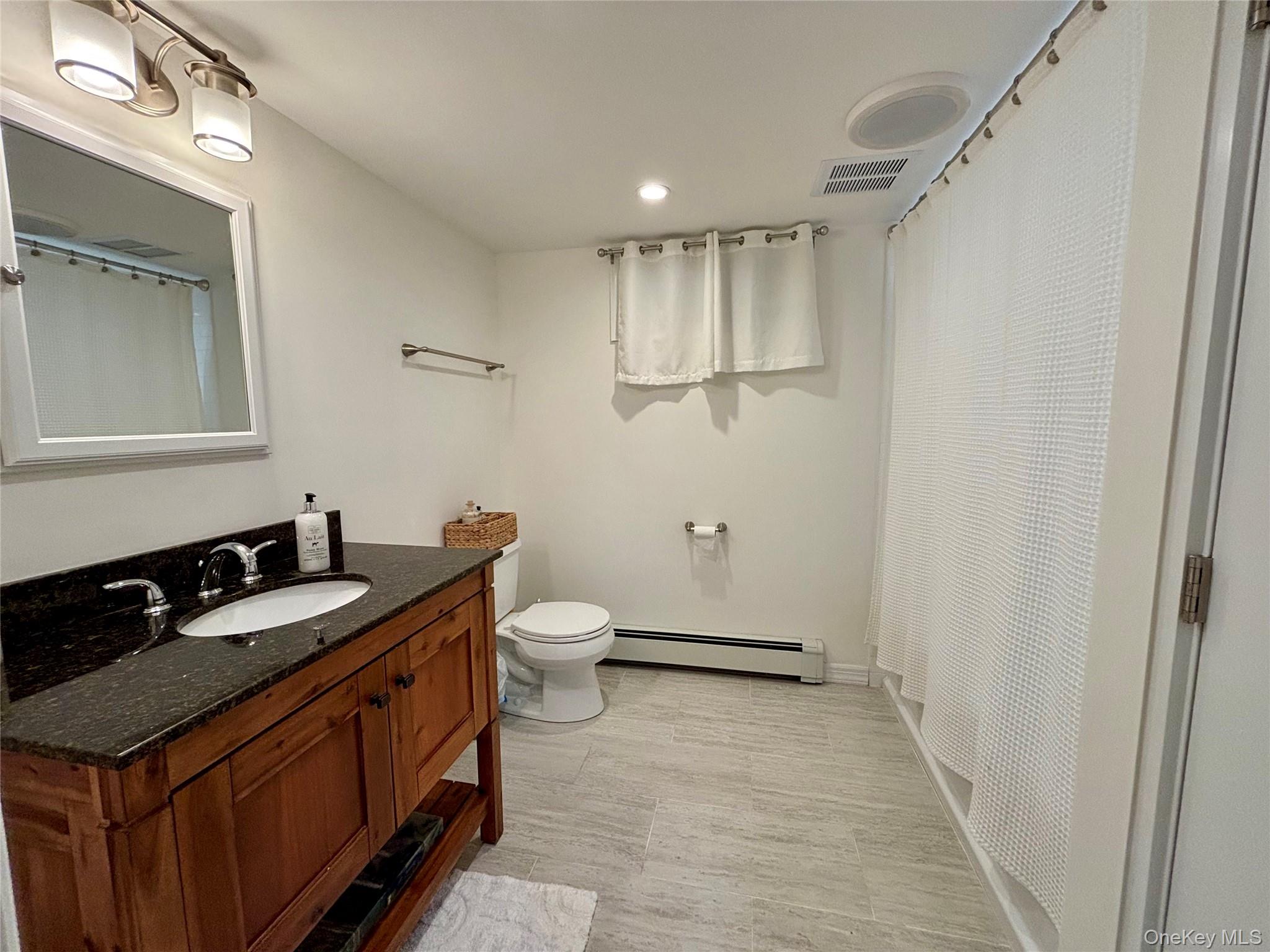 129 Lynncliff Road Hampton Bays, NY 11946 - Photo 20 of 24 a spacious bathroom with a sink a toilet a mirror and vanity