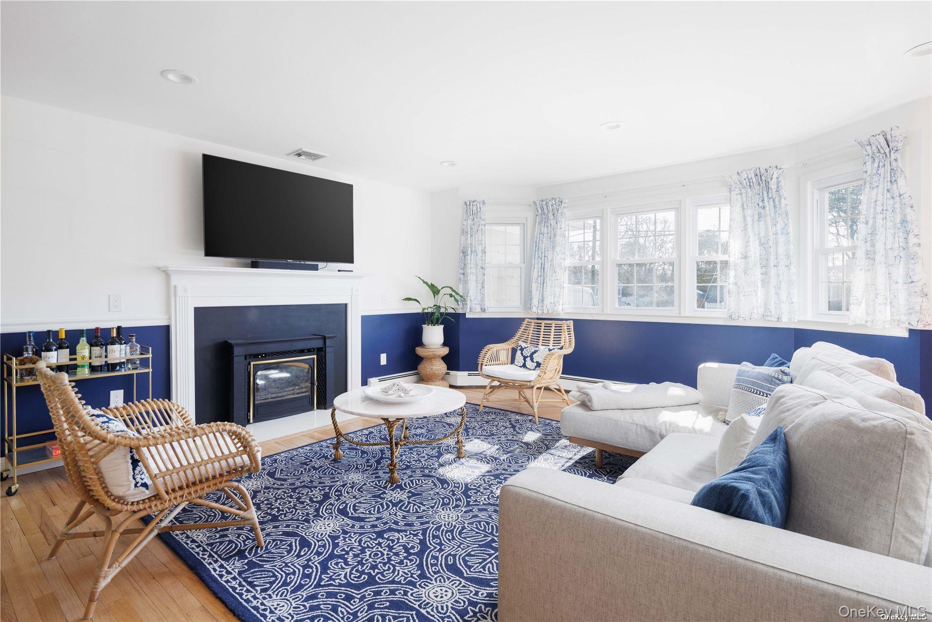129 Lynncliff Road Hampton Bays, NY 11946 - Photo 3 of 19 a living room with furniture a flat screen tv and a fireplace