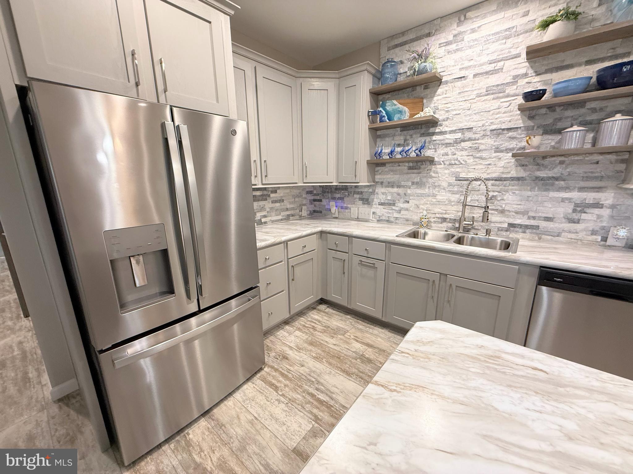 26908 Wood Duck Road, Unit 611 Long Neck, DE 19966 - Photo 37 of 80 a kitchen with stainless steel appliances a refrigerator a sink a stove a washer dryer and white cabinets