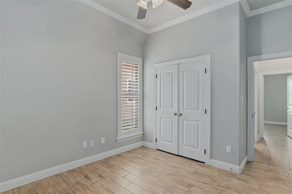 a view of an empty room with wooden floor and closet area