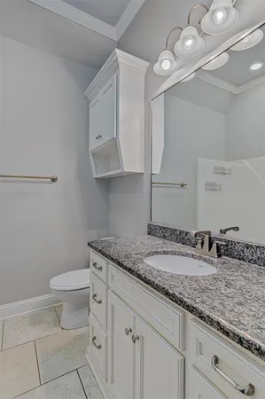 a bathroom with a granite countertop sink a toilet and a mirror