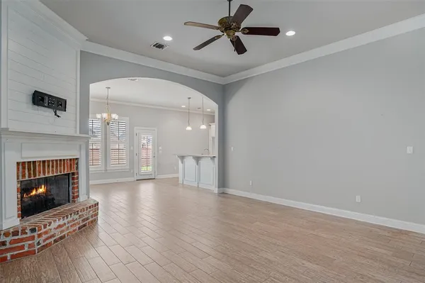 a view of a livingroom with a fireplace a ceiling fan and wooden floor