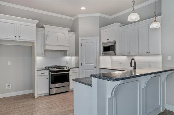 a kitchen with granite countertop a sink a stove and cabinets