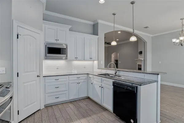 a kitchen with a sink dishwasher a stove and a fireplace with wooden floor