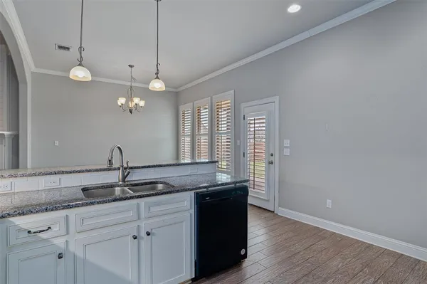 a kitchen with granite countertop a sink cabinets and wooden floor