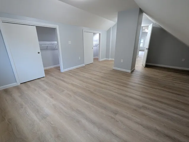 a view of an empty room with wooden floor and closet