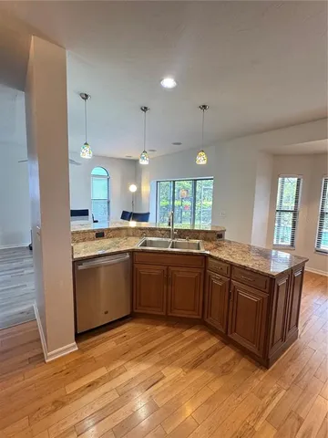 a kitchen with stainless steel appliances granite countertop a sink a stove a refrigerator cabinets and wooden floor