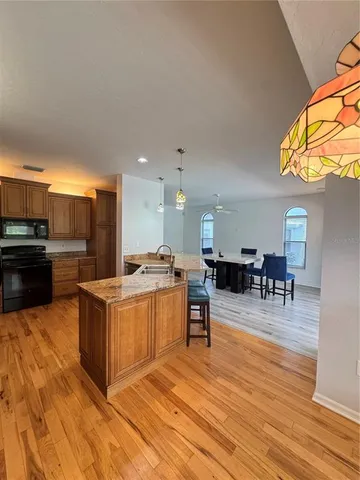 a kitchen with stainless steel appliances kitchen island granite countertop a table chairs and a refrigerator