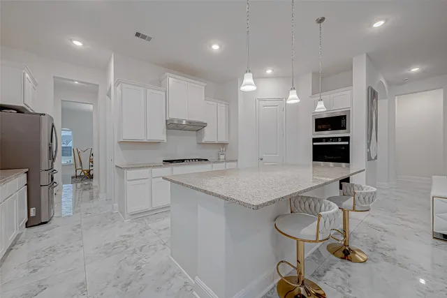 a kitchen with stainless steel appliances granite countertop a sink a refrigerator and a stove