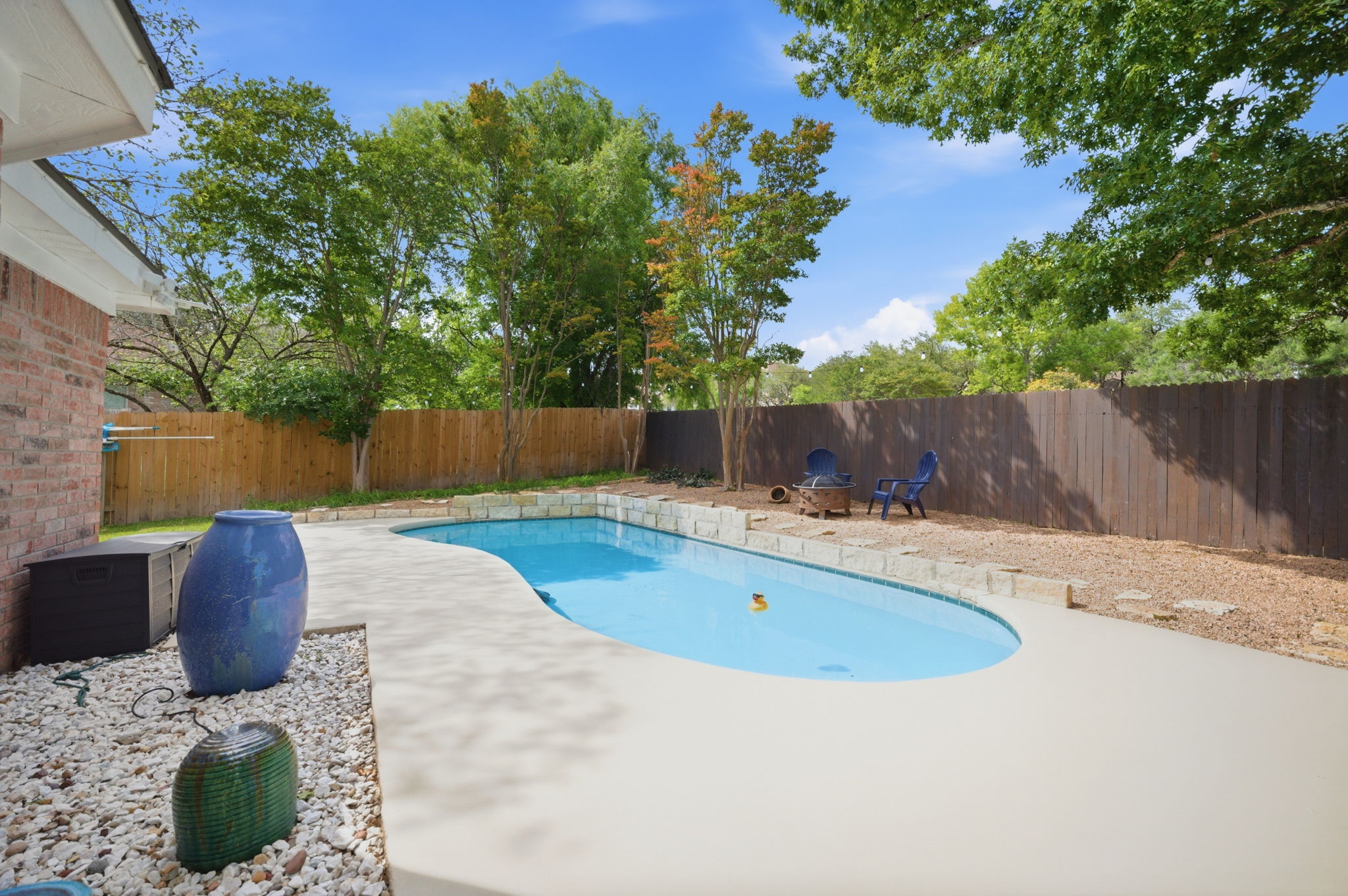 9024 Heiden Lane Austin, TX 78749 - Photo 21 of 28 Backyard featuring a freeform swimming pool with stone coping, a concrete patio surround, and a wood privacy fence