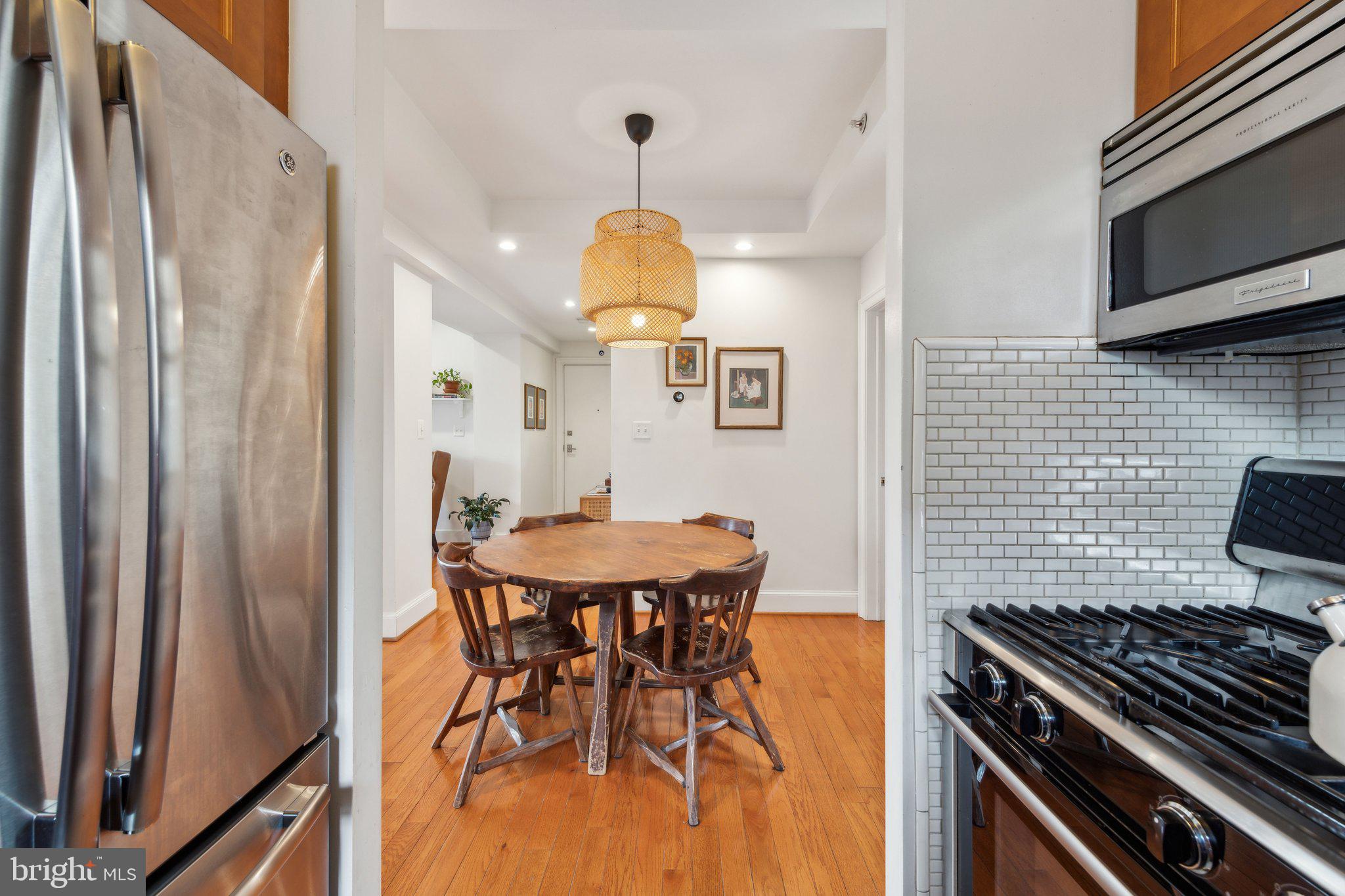 3220 17th Street Northwest, Unit 309 Washington, DC 20010 - Photo 3 of 25 a kitchen with stainless steel appliances a table chairs and a refrigerator