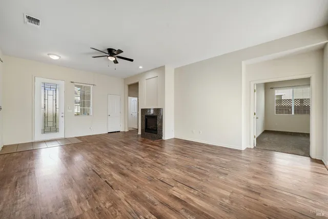 a view of an empty room with window and wooden floor