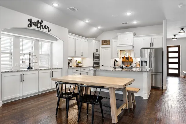 a kitchen with stainless steel appliances granite countertop a dining table chairs refrigerator sink and cabinets