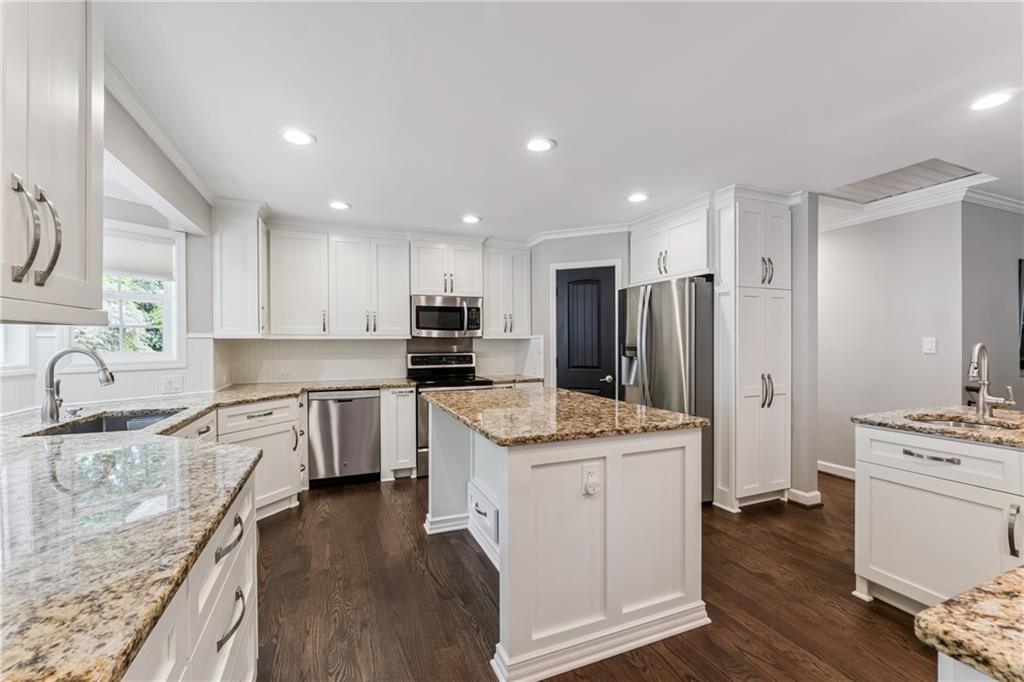 3701 Shallowford Road Marietta, GA 30062 - Photo 5 of 49 a kitchen with a sink stove a refrigerator and white cabinets with wooden floor