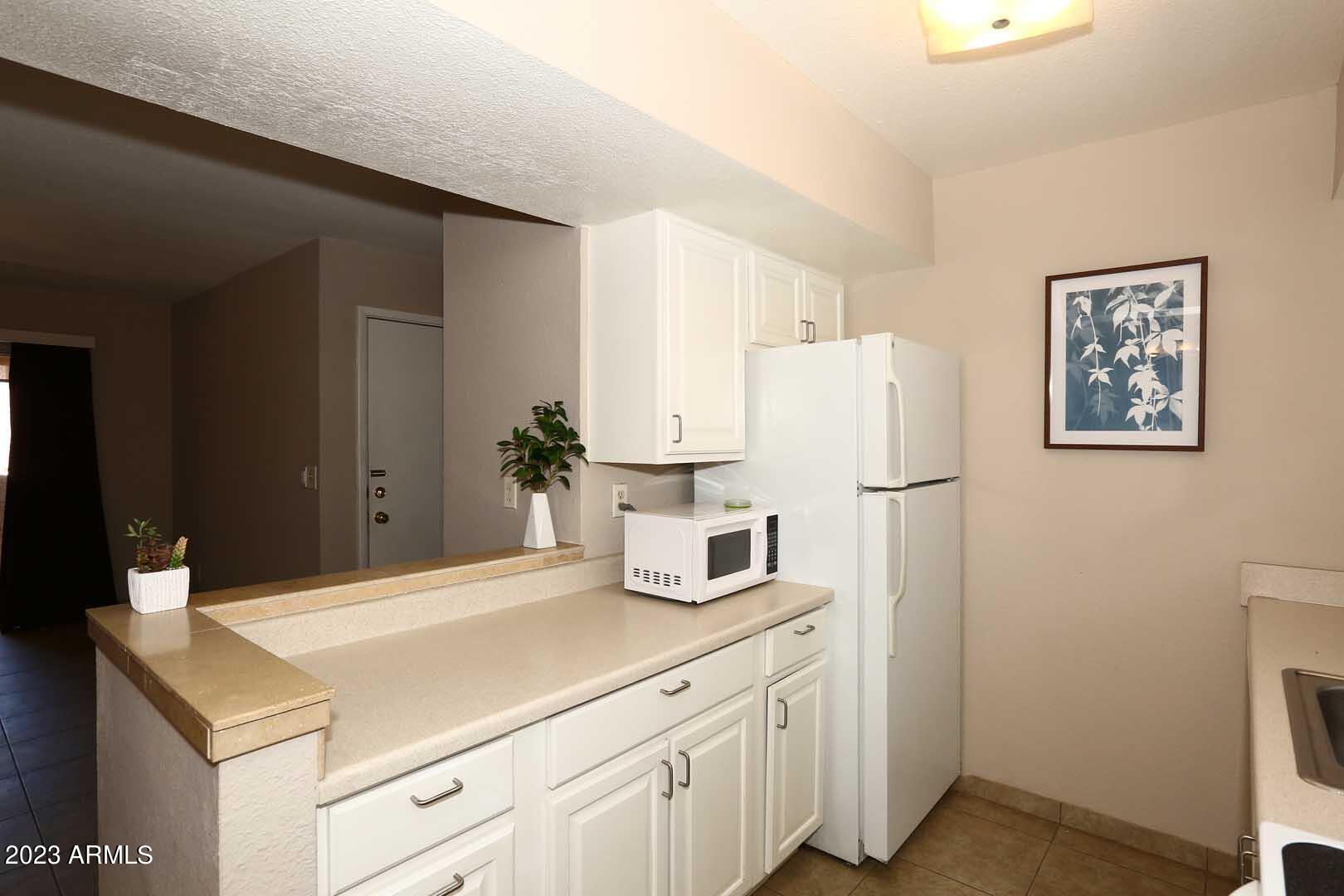 4554 East Paradise Village Parkway North, Unit 259 Phoenix, AZ 85032 - Photo 12 of 30 a kitchen with a refrigerator and white cabinets