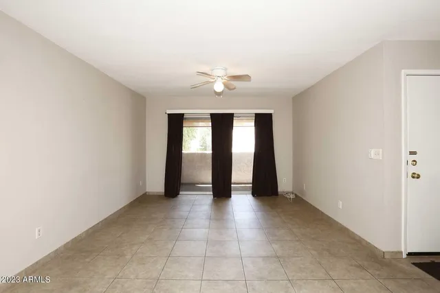 an empty room with chandelier fan and windows