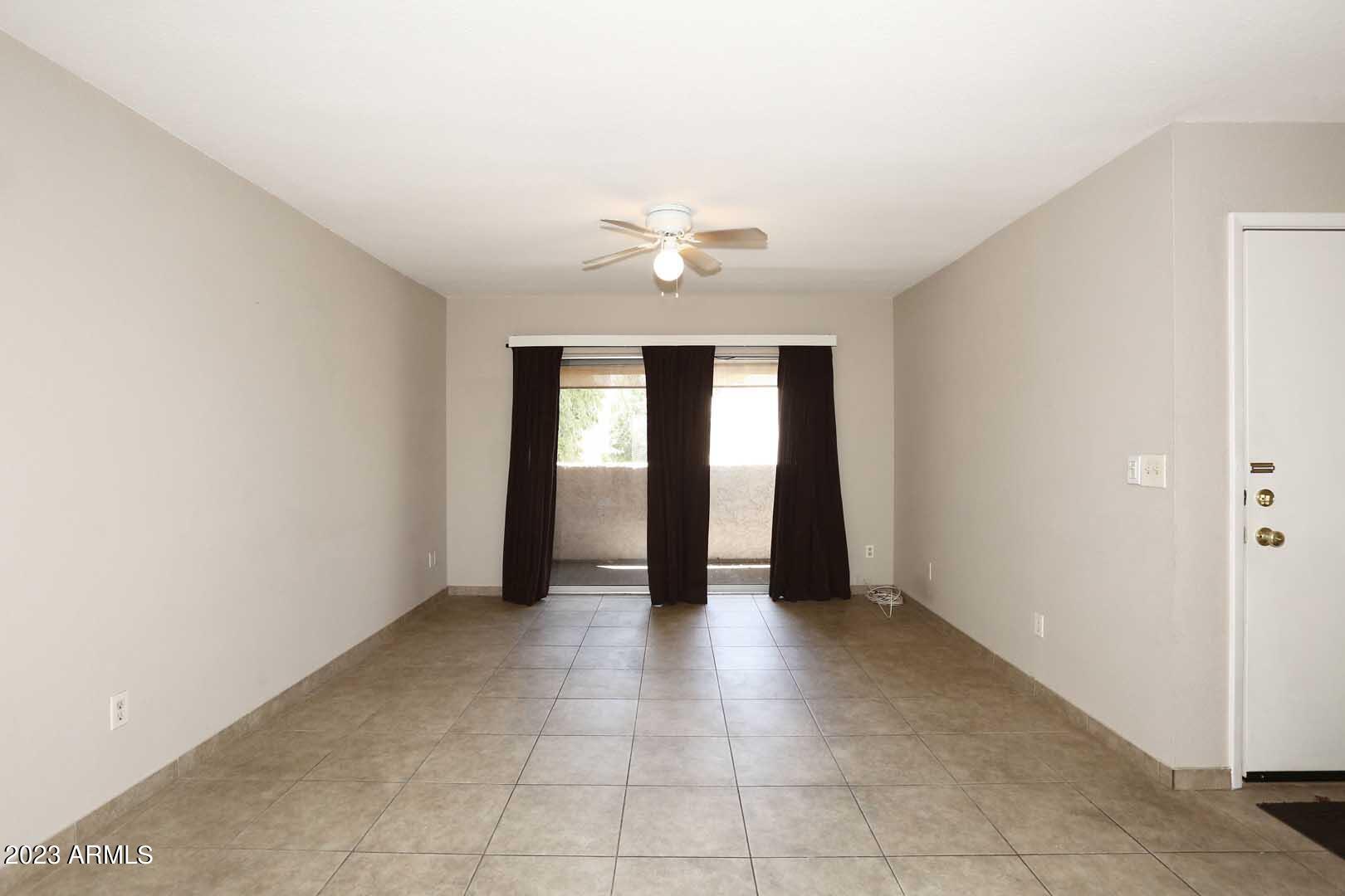 4554 East Paradise Village Parkway North, Unit 259 Phoenix, AZ 85032 - Photo 4 of 30 an empty room with chandelier fan and windows