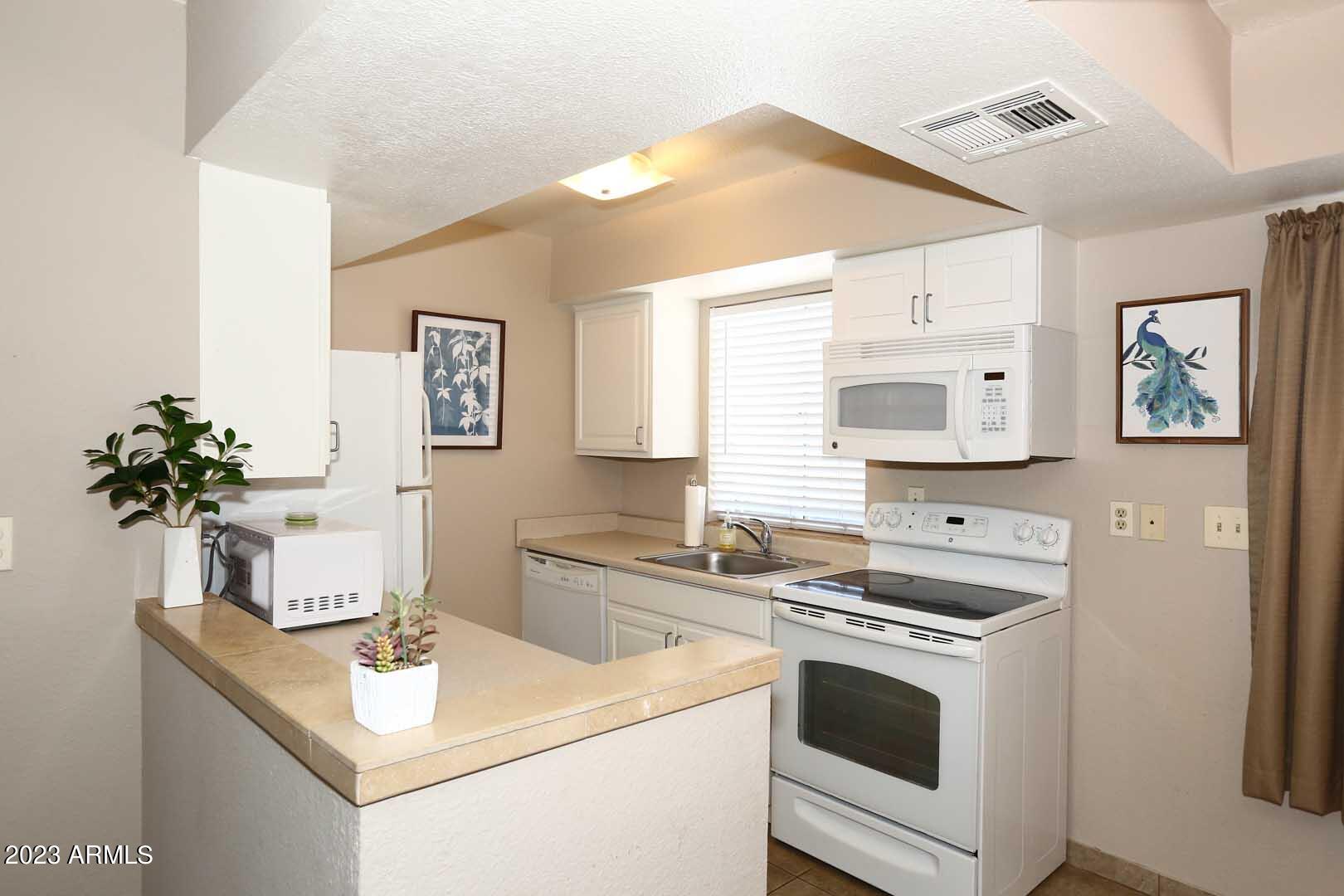 4554 East Paradise Village Parkway North, Unit 259 Phoenix, AZ 85032 - Photo 9 of 30 a kitchen with stainless steel appliances cabinets a sink and a potted plant