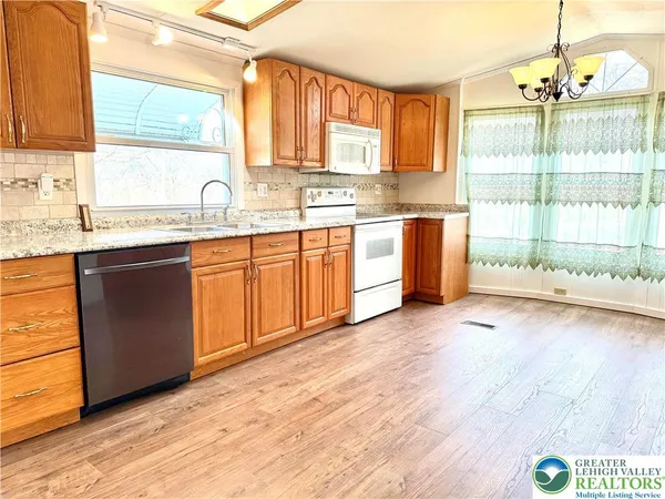 a kitchen with granite countertop a stove a sink dishwasher a refrigerator and wooden floor