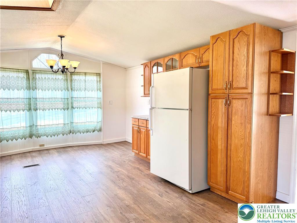 204 Molly Pitcher Road Mount Bethel, PA 18343 - Photo 10 of 34 a view of a refrigerator in kitchen and an empty room with wooden floor