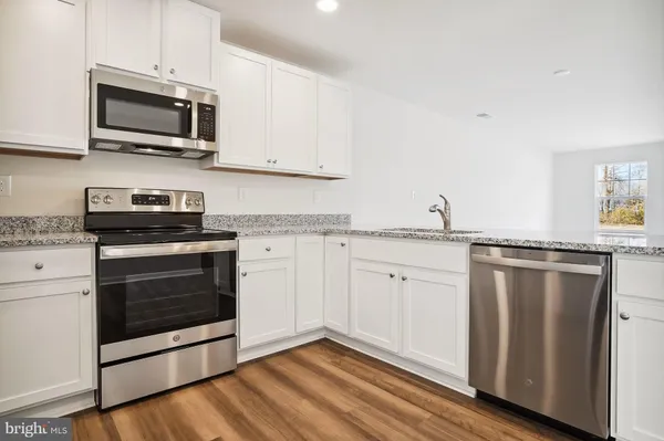 a kitchen with granite countertop cabinets stainless steel appliances and wooden floor